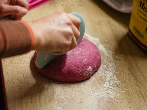 Hand dividing the dough for beetroot burger buns