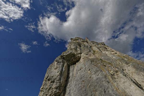 Striking limestone rock formation Burgstein with blue and white sky in the upper Altmuehltal surrounded by green vegetation