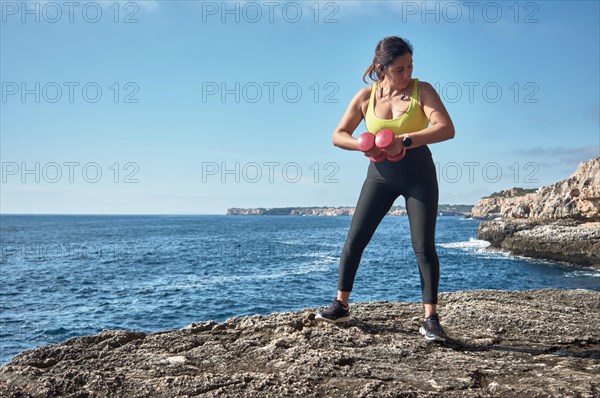 FITNESS WOMAN IN SPORTS SET TRAINING WITH ELASTIC BAND