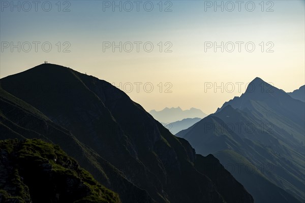 Mountain ridge with mountaineers and Swiss mountains and Lake Thun in the background at sunrise