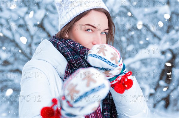 Portrait of a beautiful woman against the background of a winter forest in New Year's mittens. Concept of Christmas