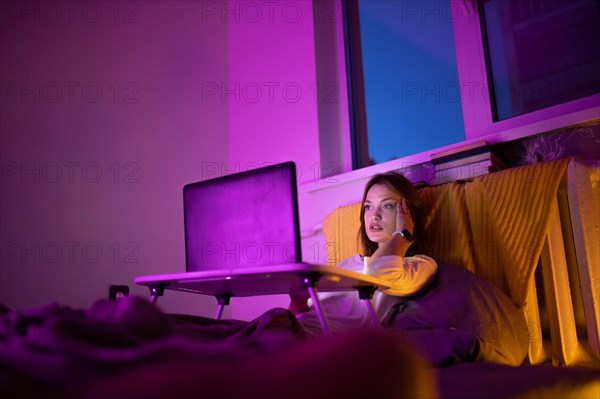 A young pretty girl works at home on a laptop