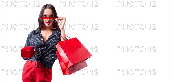 Beautiful sexy girl in glasses posing in the studio with red packages and a box for jewelry. White background. Shopping concept.
