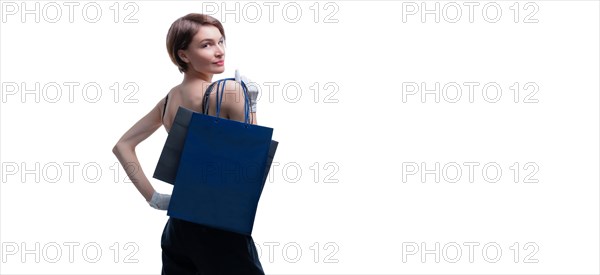 Beautiful young woman in white gloves threw a black craft bag over her shoulder. Shopaholics concept. Spenting. Gifts for the holidays. Black Friday. Shopping centers