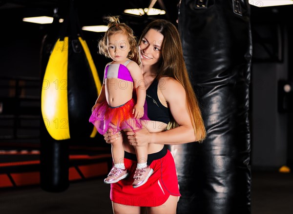 Charming sportswoman with her daughter posing during training. Joint family trainings