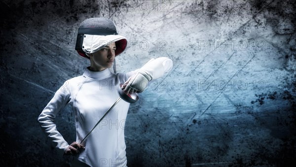 Charming girl dressed as a fencer posing with a mask and a sword. The concept of fencing.