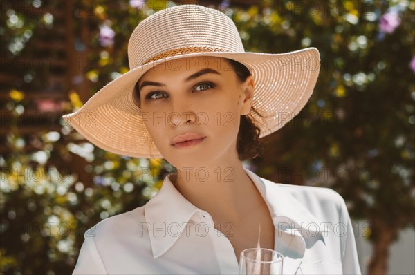 Portrait of a charming girl in a wide-brimmed hat on a garden background. The concept of rest