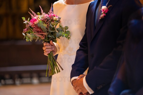 Detail of the bride and groom sitting at a church wedding
