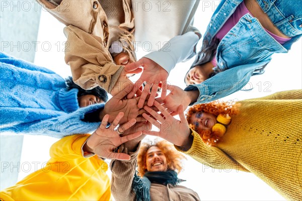 Low angle view of group of diverse young people join hands in circle