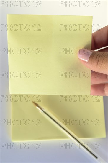 Woman's hand with painted nails holding blank letter paper on pure white background