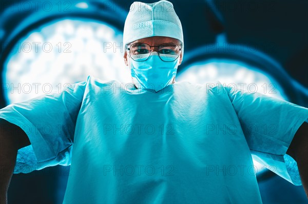 Portrait of a doctor in a mask on a background of surgical lamps. Medicine concept.