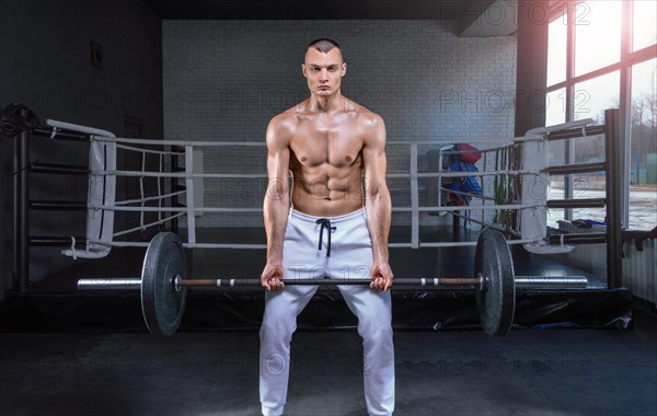 Handsome young man working out with a barbell in the gym. Biceps pumping. Fitness and bodybuilding concept.