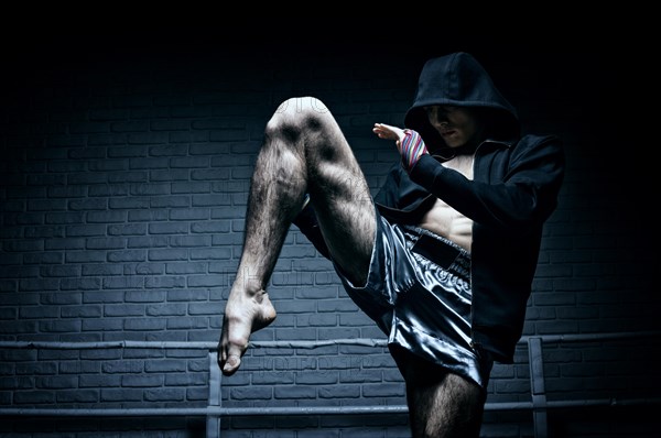 Thai boxer in the ring hits with a knee. The concept of sports