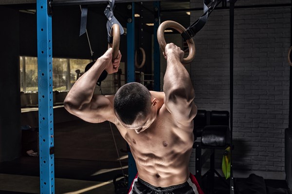 Athlete does warm-up on gymnastic rings. The concept of sport and healthy lifestyle.