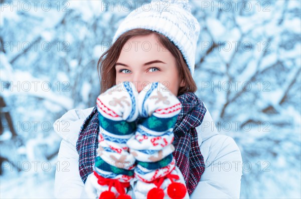 Portrait of a beautiful woman against the background of a winter forest in New Year's mittens. Concept of Christmas