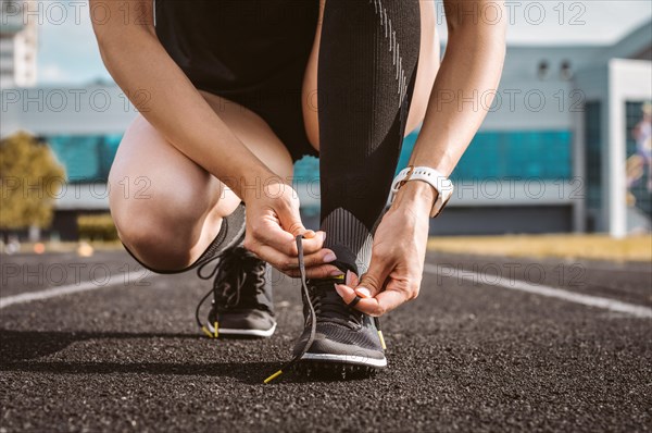 Image of an athlete tying her shoelaces with spikes. Running concept.