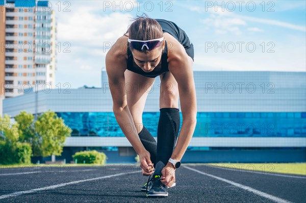 Image of an athlete tying her shoelaces with spikes. Running concept.