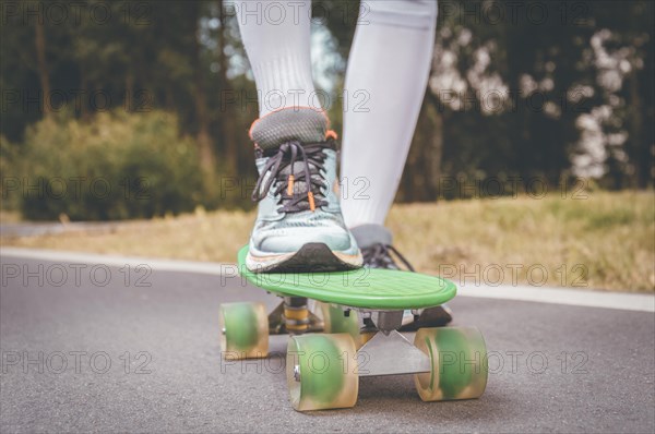 Images of a leg standing on a skateboard. Sunny evening in the park. Skateboarding concept.