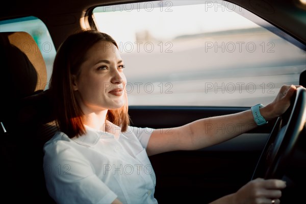 Young beautiful girl taxi driver smiling behind the wheel