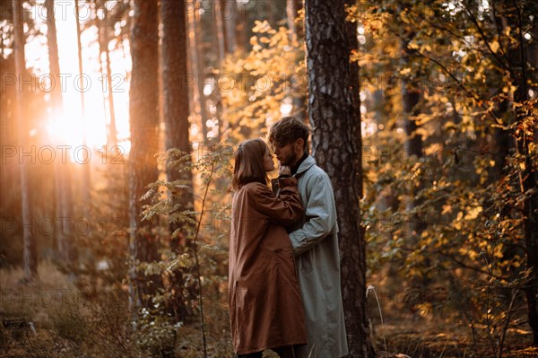 Beautiful fashionable couple in love in the forest at sunset in autumn