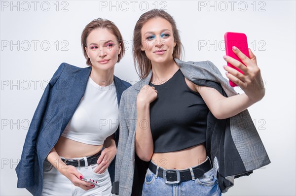 Portrait of two laughing women in blazers taking a selfie. Friendship concept.