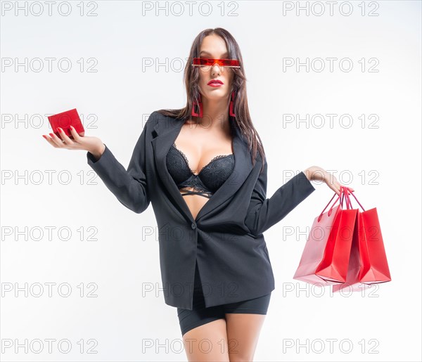 Beautiful sexy girl in glasses posing in the studio with red packages and a box for jewelry. White background. Shopping concept.