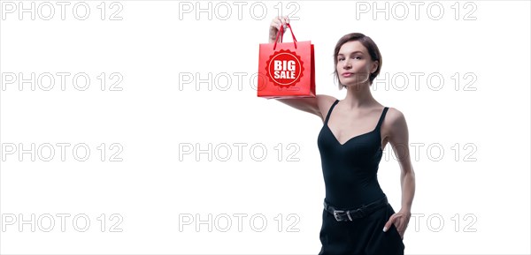 Portrait of stylish adult woman posing in studio on white background with red gift bag. Valentine's Day concept. Holidays and gifts.