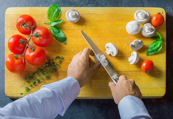 Professional chef cuts vegetables with a sharp knife from Damascus steel.