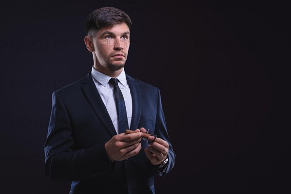 Portrait of a stylish man in a suit with a cigar. Business concept.