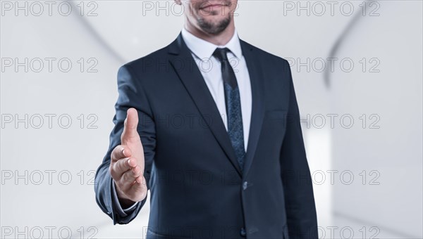 Image of a stylish man in a suit holding out his hand for a handshake. Business concept.