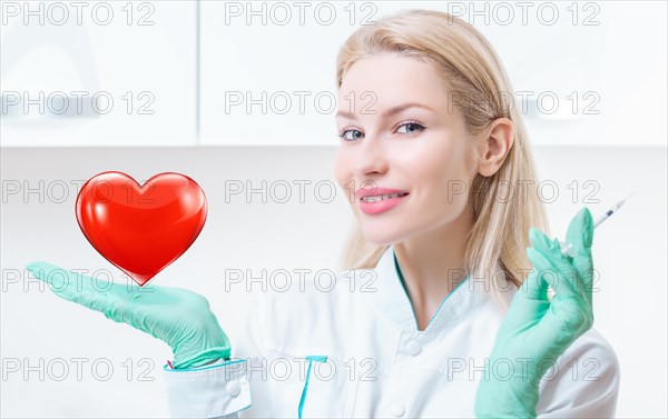 Portrait of a blonde girl in a medical gown. She holds a red heart in her palm. Concept of Cardiology and Transplantology.