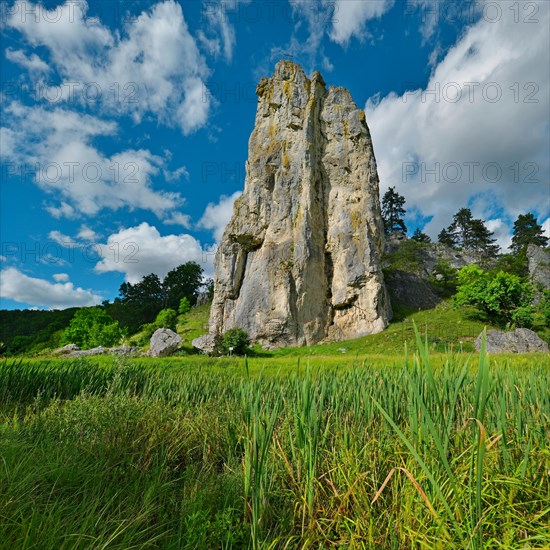 Striking limestone rock formation Burgstein with blue and white sky in the upper Altmuehltal surrounded by green vegetation