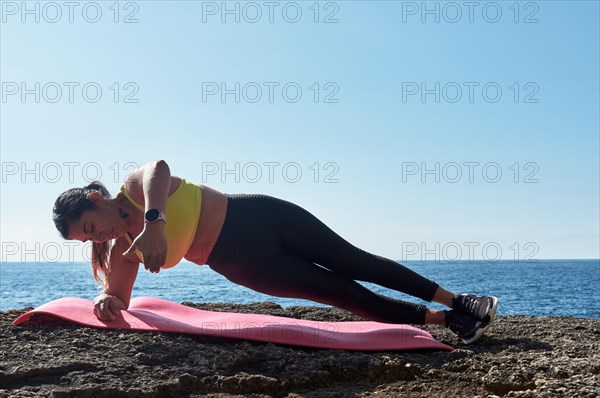 FITNESS WOMAN IN SPORTS SET TRAINING WITH ELASTIC BAND