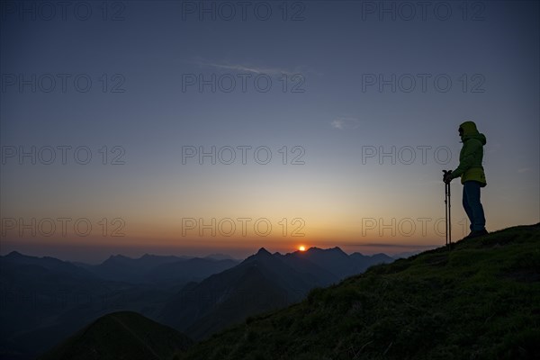 Mountaineer on mountain ridge with Rothorn peak in the background at sunrise