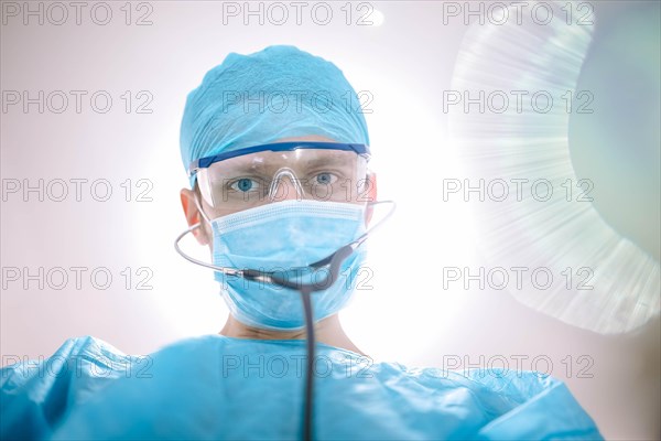 Male surgeon doctor in the operating room looking at the patient at the camera