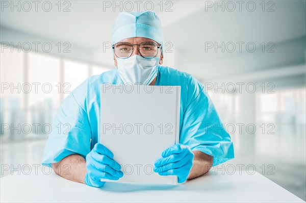 The doctor is holding a white reference book in front of him. Medicine concept.