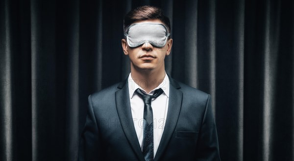 Portrait of a man in a mask for sleeping. He stands against the backdrop of a curtain. The concept of blind dates