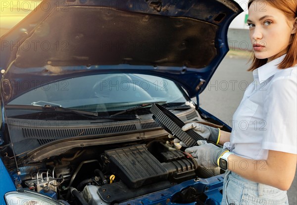 Young beautiful and hot woman auto mechanic holding a timing belt in her hands