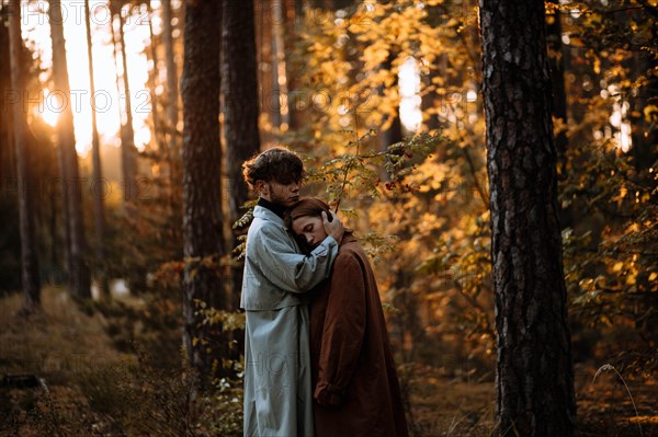 Beautiful fashionable couple in love in the forest at sunset in autumn