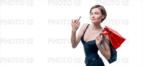 Portrait of a beautiful woman with red packages. She shows a fuck sign and smiles. Shopaholic concept. Shopping centers. Sales.