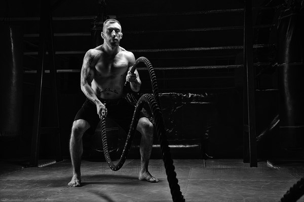 The athlete works with crossfit ropes in the gym. The concept of sports