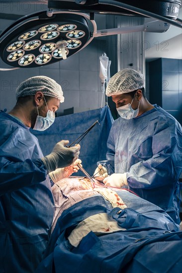 Two male surgeon-physicians operating on a scoliosis. Surgery