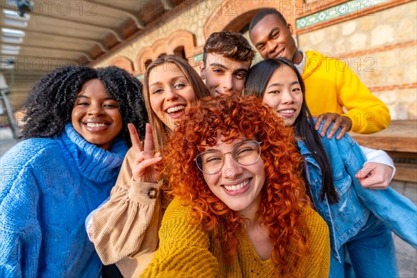 Diverse young friends taking a selfie smiling and gesturing success in an urban space