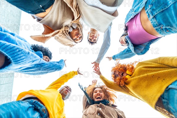 Low angle view photo of a smiling multi-ethnic group join and raising hands