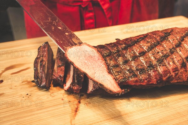 A piece of meat is sliced after grilling