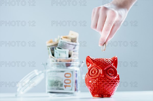 Female hand puts a coin in a piggy bank in the shape of an owl. Thrift concept.