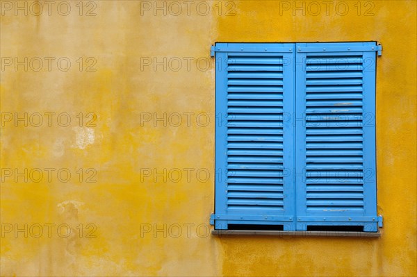 Blue shutter on yellow plaster wall