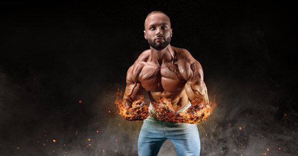 Isolated athlete on a background of smoke with burning hands. Fat burning concept. Bodybuilding.