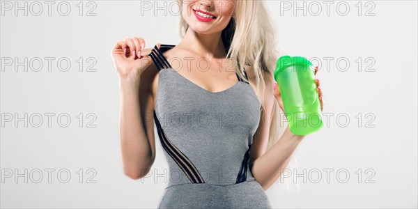 Charming model posing in studio with shaker in hands.