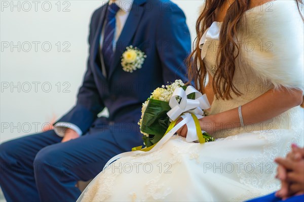 Detail of the bride and groom sitting at a church wedding